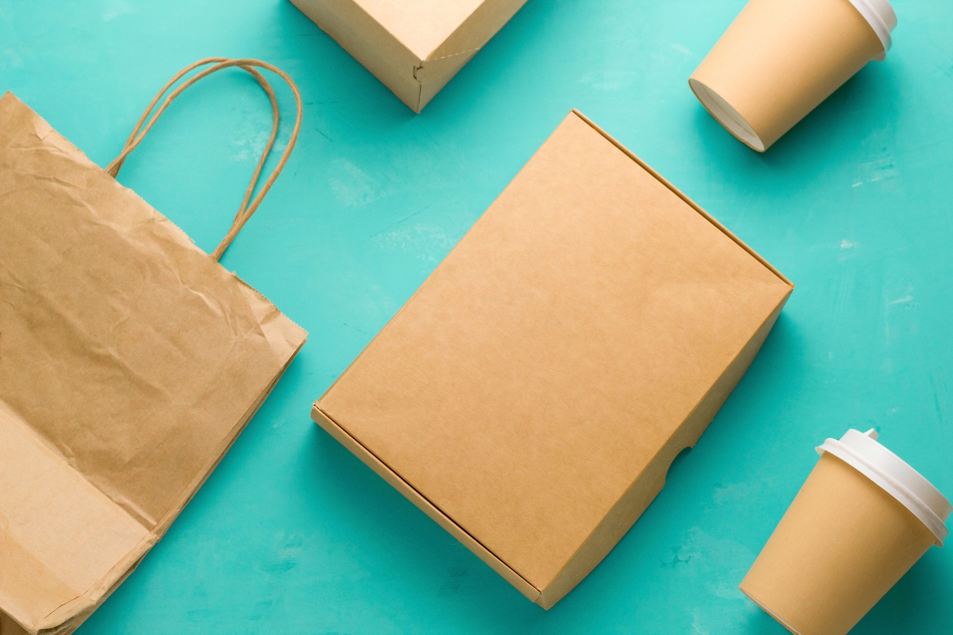 flat lay recyclable types of paper  packaging on a blue background, paper bag, disposable glass, cardboard box
